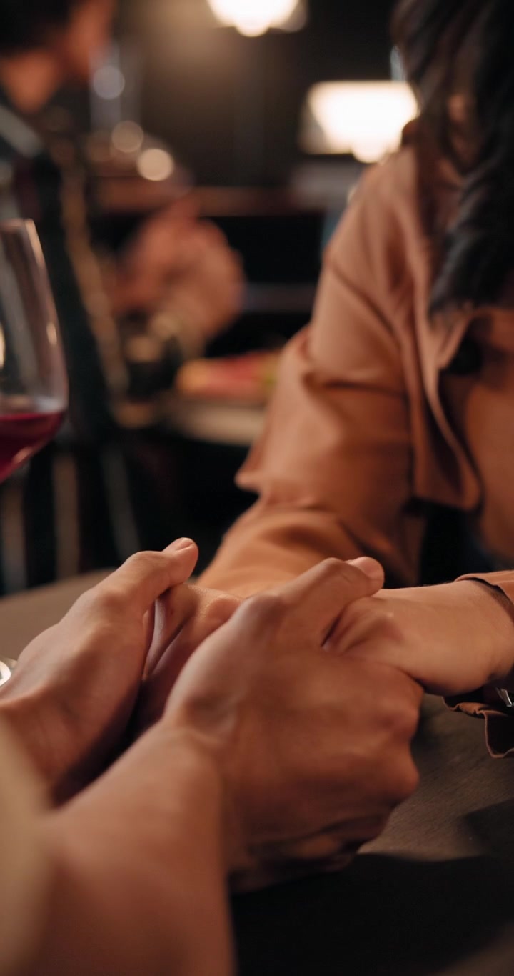 Coppia che si tiene per mano durante una cena romantica