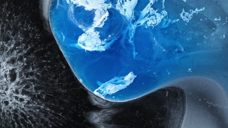 Abstract macro view of blue alcoholic ink mixing with liquid, creating dynamic patterns