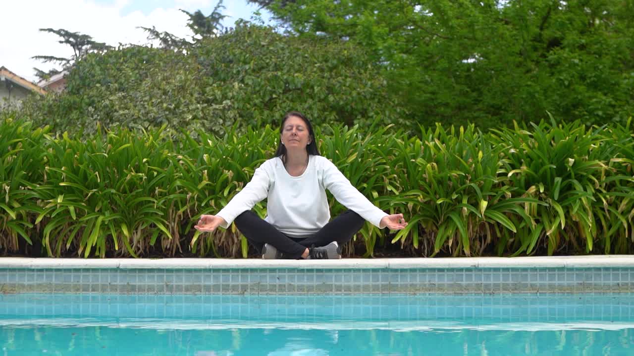 Donna seduta a bordo piscina che medita