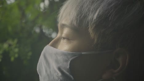 young asian man wearing facemask due to covid-19 in singapore. - close up, side view