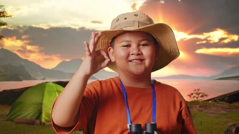 smiling boy with binoculars and ok sign at a sunset camping trip