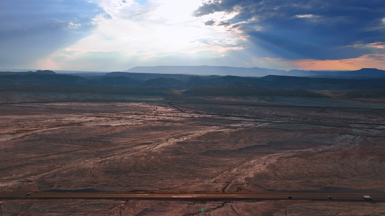 Aerial drone view of Utah's desert cliffs and flatlands during sunset with light breaking through storm clouds
