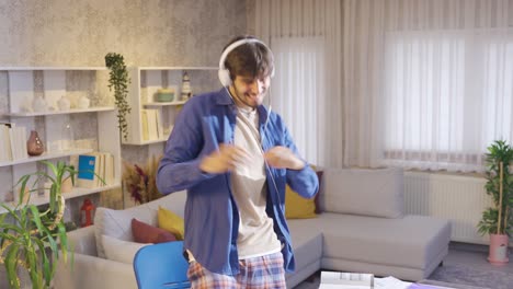 male student looking at his laptop and receiving good news dancing happily and having fun.