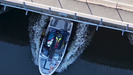 drone captures a boat maneuvering along a dock in gold coast, australia. clear skies and calm waters enhance the serene atmosphere