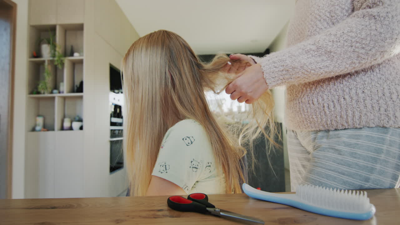 Woman trying to untangle her teenage daughter's long hair