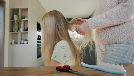 Woman-trying-to-untangle-her-teenage-daughter's-long-hair