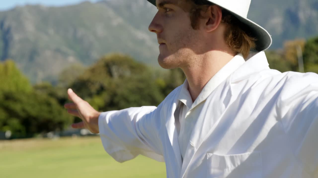 크리켓 심판 이 경기 도중 넓은 공 을 신호 하고 있다