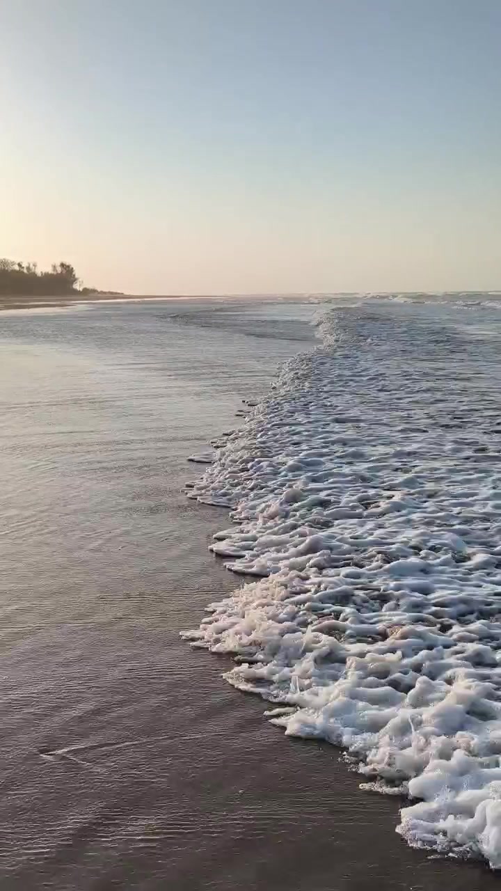 Dolci Onde dell'Oceano che si Infrangono su una Spiaggia Sabbiosa al Tramonto