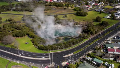 Hot-water-hot-pool-steaming-in-Kuirau-Park-in-Rotorua-city,-New-Zealand---aerial-drone