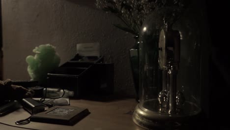 torsion clock spinning on a cluttered side table lit by a small lamp