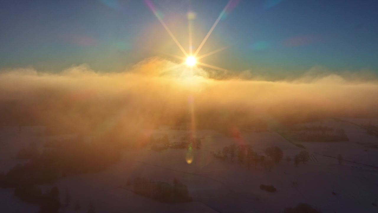 Golden winter sunrise over misty snow covered landscape