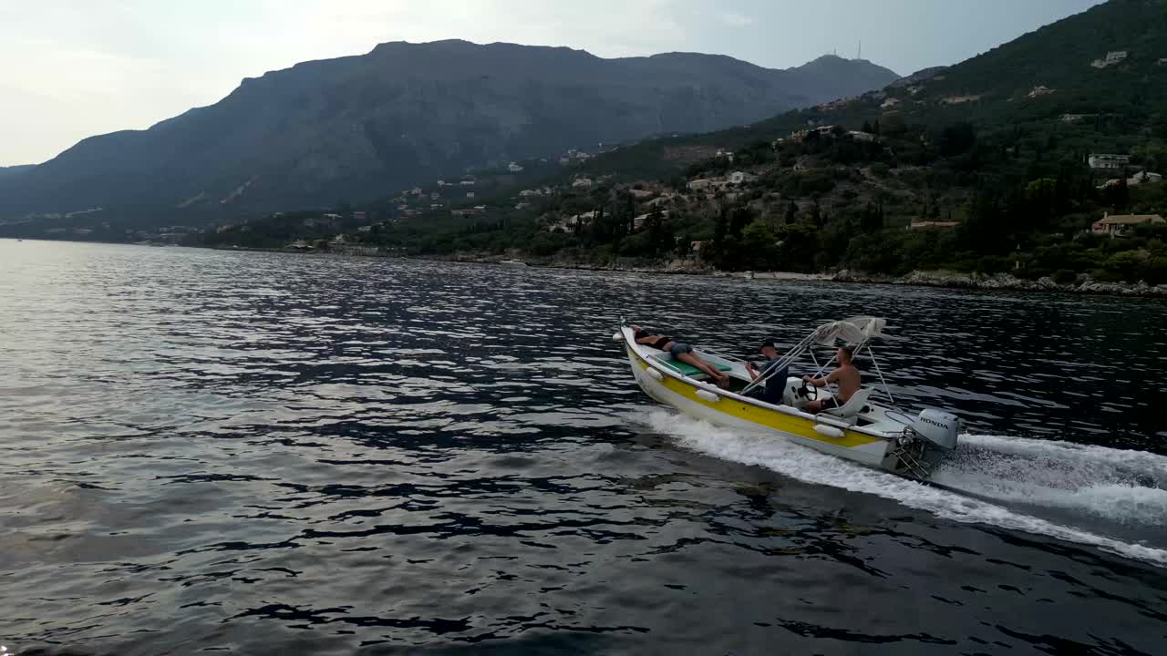 A drone captures a speedboat slicing through the ocean’s calm, blue waters, leaving a trail of white waves in its wake, creating a thrilling scene.
