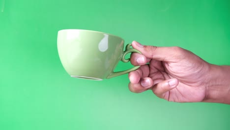 hand holding a light green coffee cup