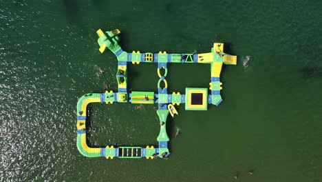 aerial bird eye shot off inflatable water games forming island shape with kids playing at the sea