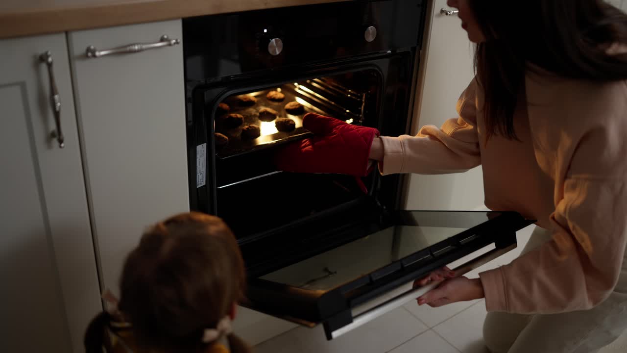 Madre e hija sacan pasteles del horno en la cocina.