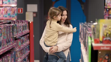 Concepto-De-Compras.-Madre-E-Hija-Eligen-Juguetes-En-El-Estante-Del-Centro-Comercial