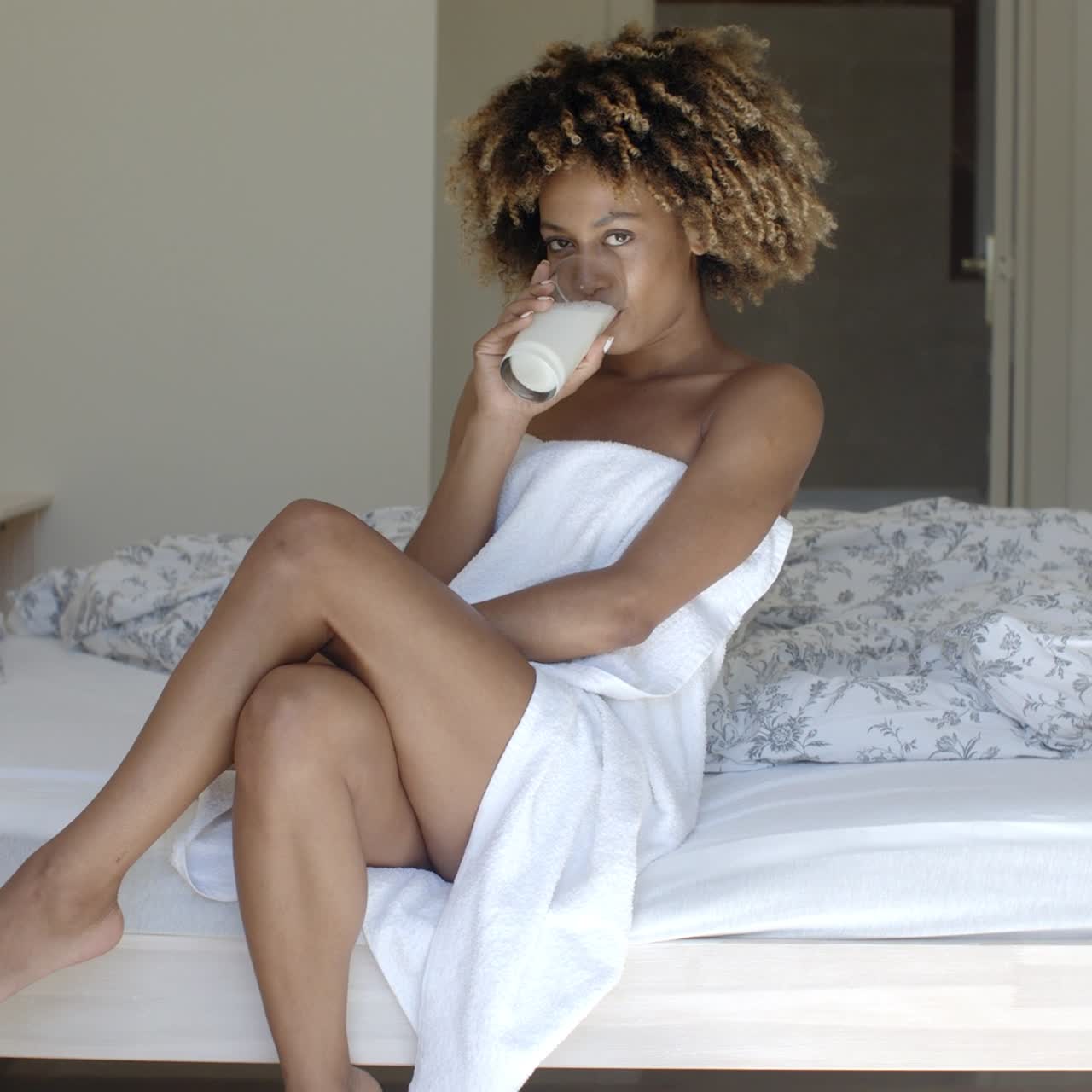 Bella ragazza che beve latte sul letto