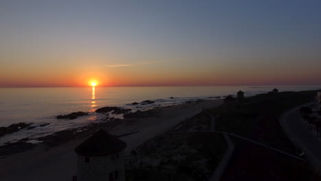 toma aérea ascendente de 4k de molinos de viento cerca de la costa del mar que revela una hermosa puesta de sol