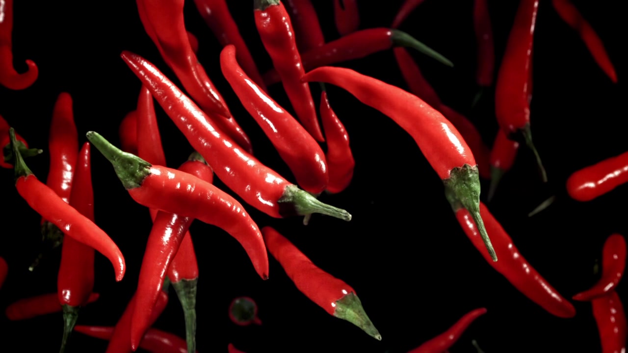 Vibrant Red Chili Peppers Falling in Slow Motion on Black Background