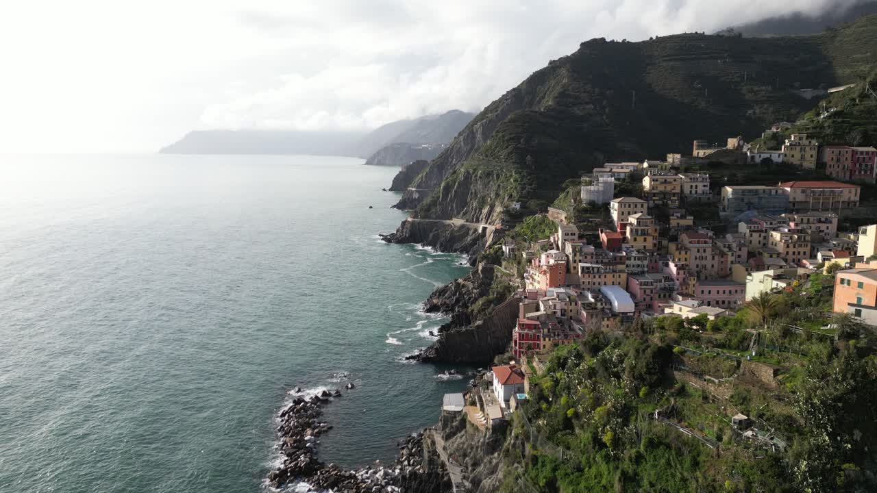 Riomaggiore, Cinque Terre, Italia, vista aerea statica del villaggio mentre le onde si infrangono sulla riva.