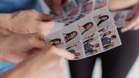 Nahaufnahme-Einer-Gruppe-Von-Freunden,-Die-Spaß-Daran-Haben,-Sich-Ausdrucke-Aus-Einer-Fotokabine-Anzuschauen