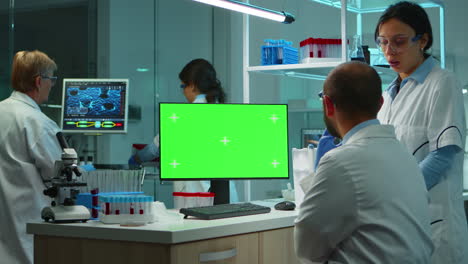 equipo de microbiólogos investigando utilizando una computadora con pantalla verde