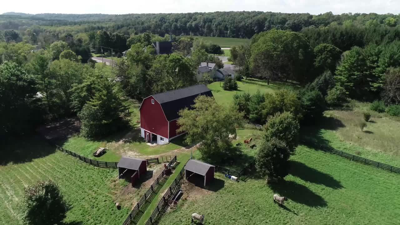 Luftoptagelse af en smuk gård og hestestald på en solrig dag.