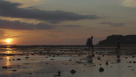 Silhouette-Of-Kids-Carrying-Trash-In-A-Low-Tide-Beach-4K