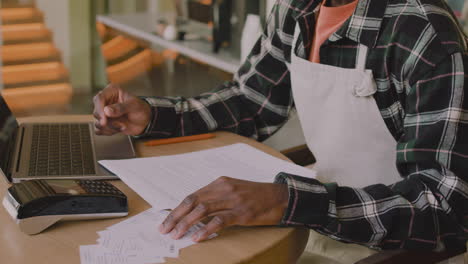 dueño de la cafetería sentado en la mesa y calculando la factura financiera en la computadora portátil 1