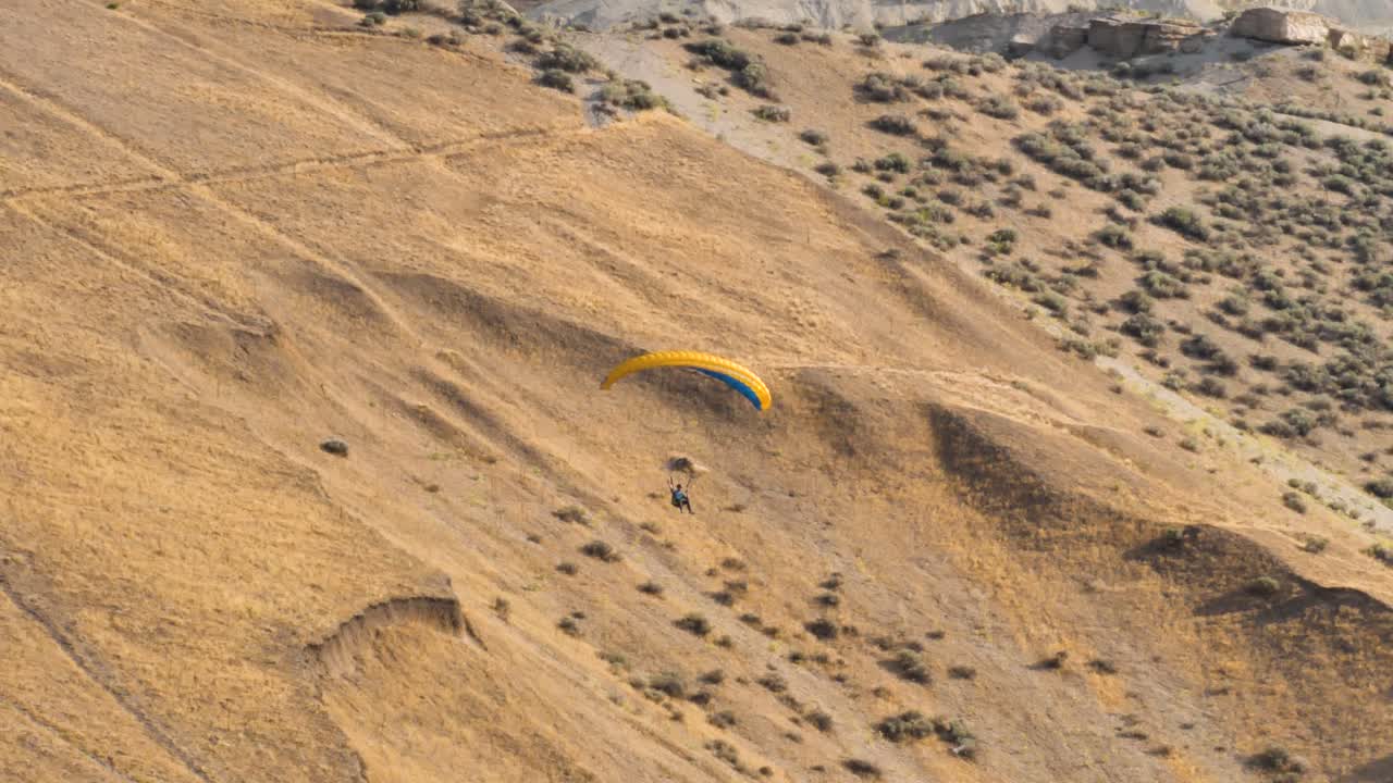 un parapente flota sobre el paisaje desértico de montaña - cámara lenta