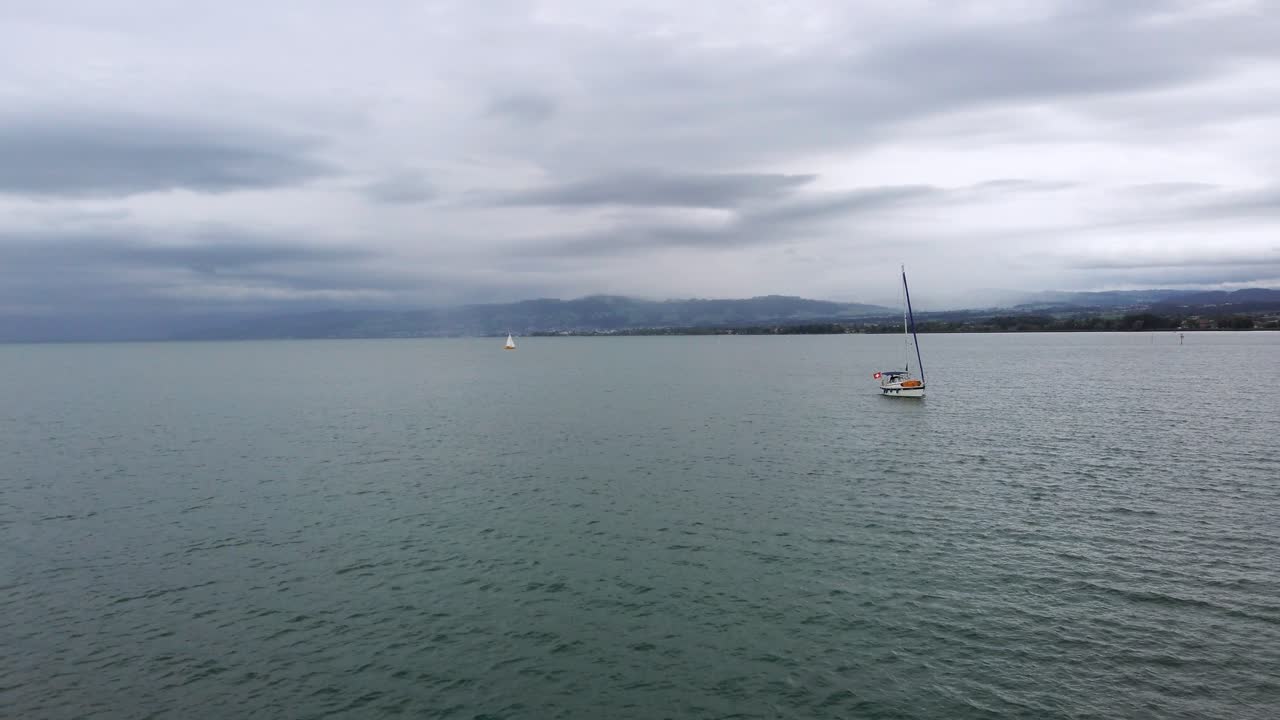 pasando lentamente por un velero en aguas oscuras y tranquilas del lago de constanza, suiza