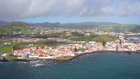 Ciudad-Costera-De-Faial-Con-Edificios-Blancos,-Tejados-Rojos-Y-Viejos-Volcanes-Detrás