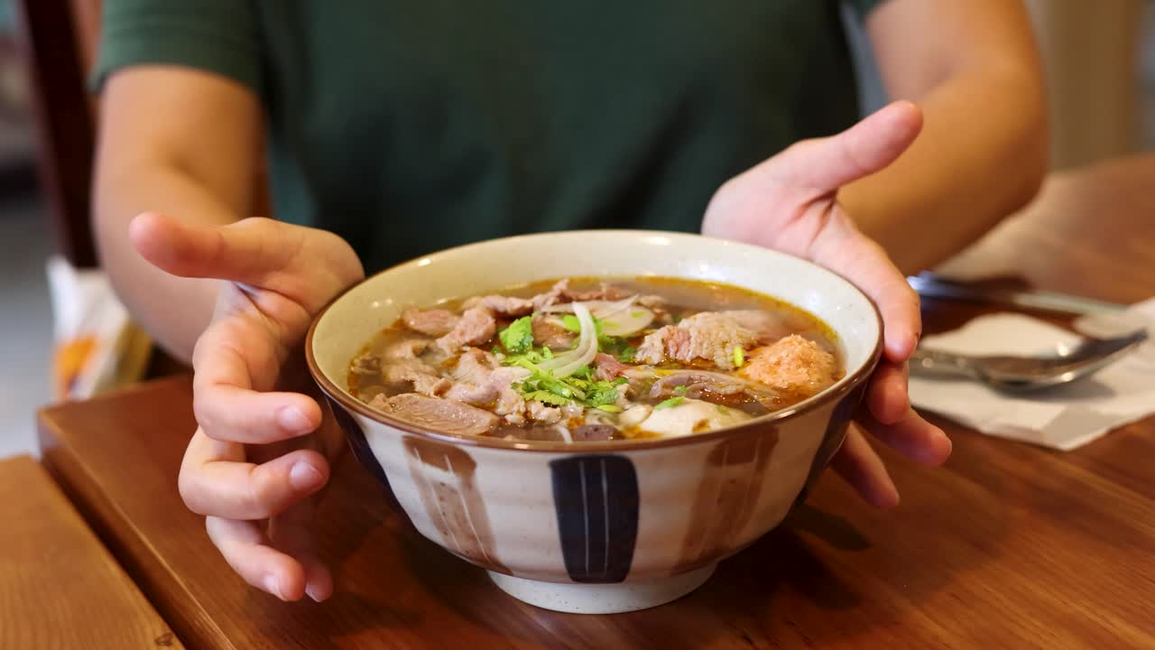 Primo piano di mani che reggono una deliziosa ciotola di zuppa di noodle vietnamita
