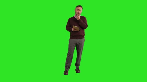 full length studio portrait of mature male teacher with notebook talking to class standing against green screen 1