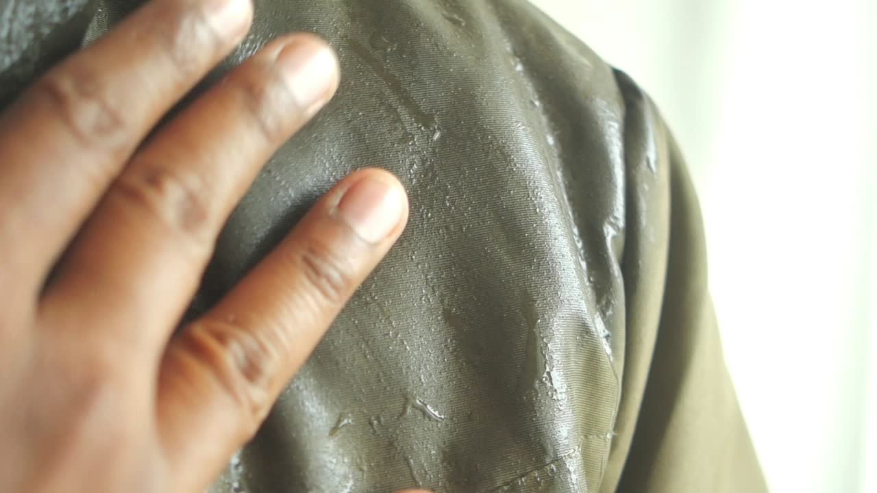 Person's wet jacket with visible sweat and hand