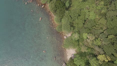 Antenne,-Vogelperspektive-Auf-Die-Tropische-Felsküste-Aus-Granit,-Klares-Türkisfarbenes-Wasser-Mit-Kleinem-Strand,-üppige-Tropische-Waldvegetation-Auf-Einer-Insel