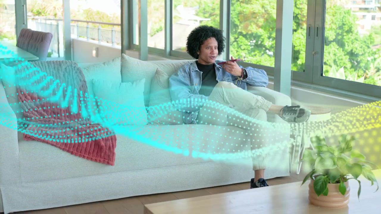 Man sitting on sofa in living room recording tech demo on phone, causing waveform overlay growing