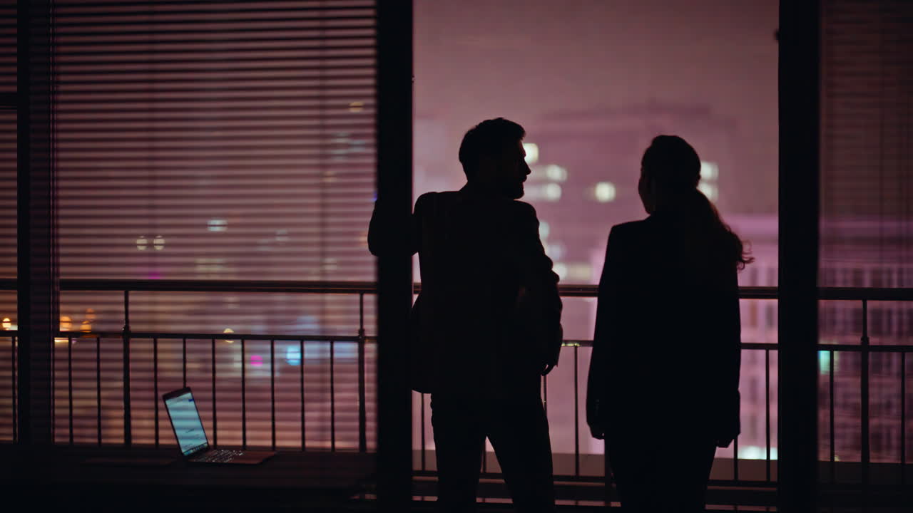 Man silhouette standing night city view window. People colleagues embracing