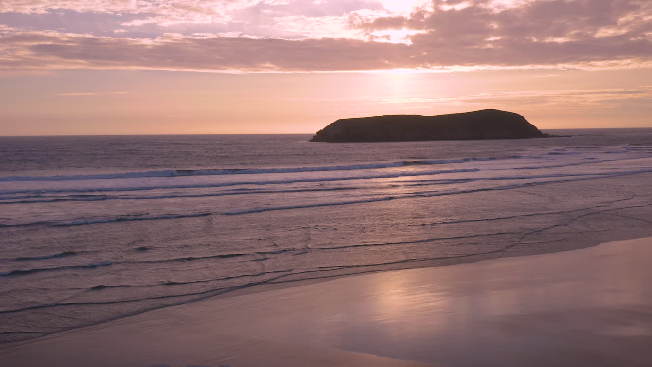 video relajante de olas suaves que llegan a la costa de oregon durante una puesta de sol rosa y malhumorada