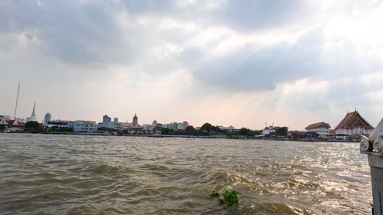 Scenic view of Chao Phraya River with cityscape, captured in natural daylight, showcasing dynamic water movement and urban skyline