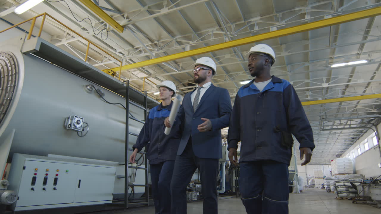 Ingegnere di produzione e operai che camminano in fabbrica