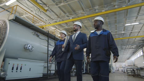 manufacturing engineer and workers walking in factory