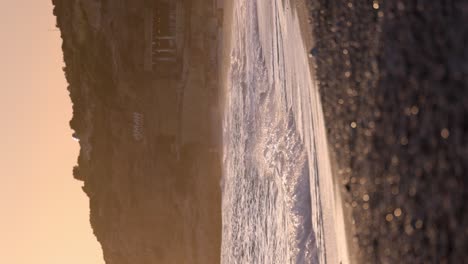 Hermosa-Playa-Durante-La-Puesta-De-Sol-Con-Olas-En-Cámara-Lenta-Rompiendo-En-La-Orilla-Vertical