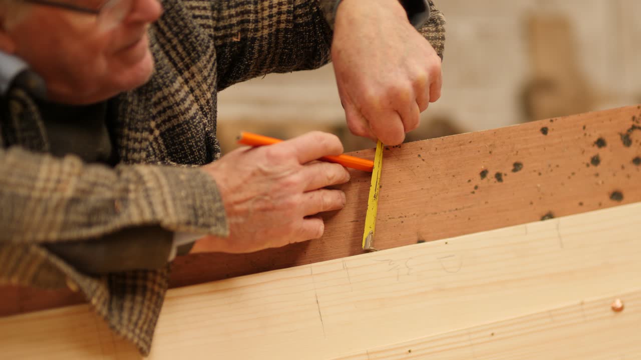 Marking dimensions on a wooden plank with a measuring tape and pencil