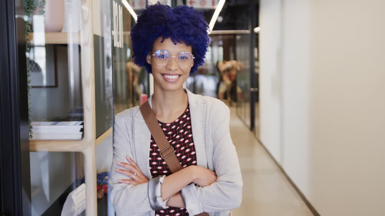 Ritratto di felice imprenditrice birazziale con capelli afro blu in ufficio, al rallentatore.