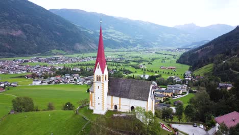 church steeple overlooking a sprawling valley village surrounded by mountains