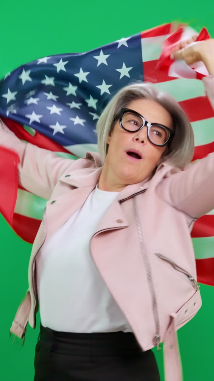 Donna felice che saluta e si avvolge nella bandiera americana su schermo verde.