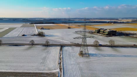 snowy agricultural landscape with roads and electrical tower from abov