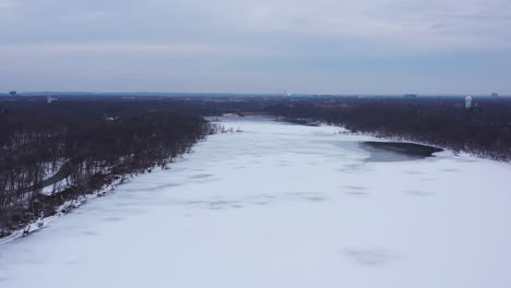 An-aerial-view-from-a-drone,-over-a-long-and-wide-lake-during-a-cloudy-sunrise