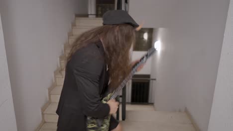 man playing guitar on stairs with devil horns